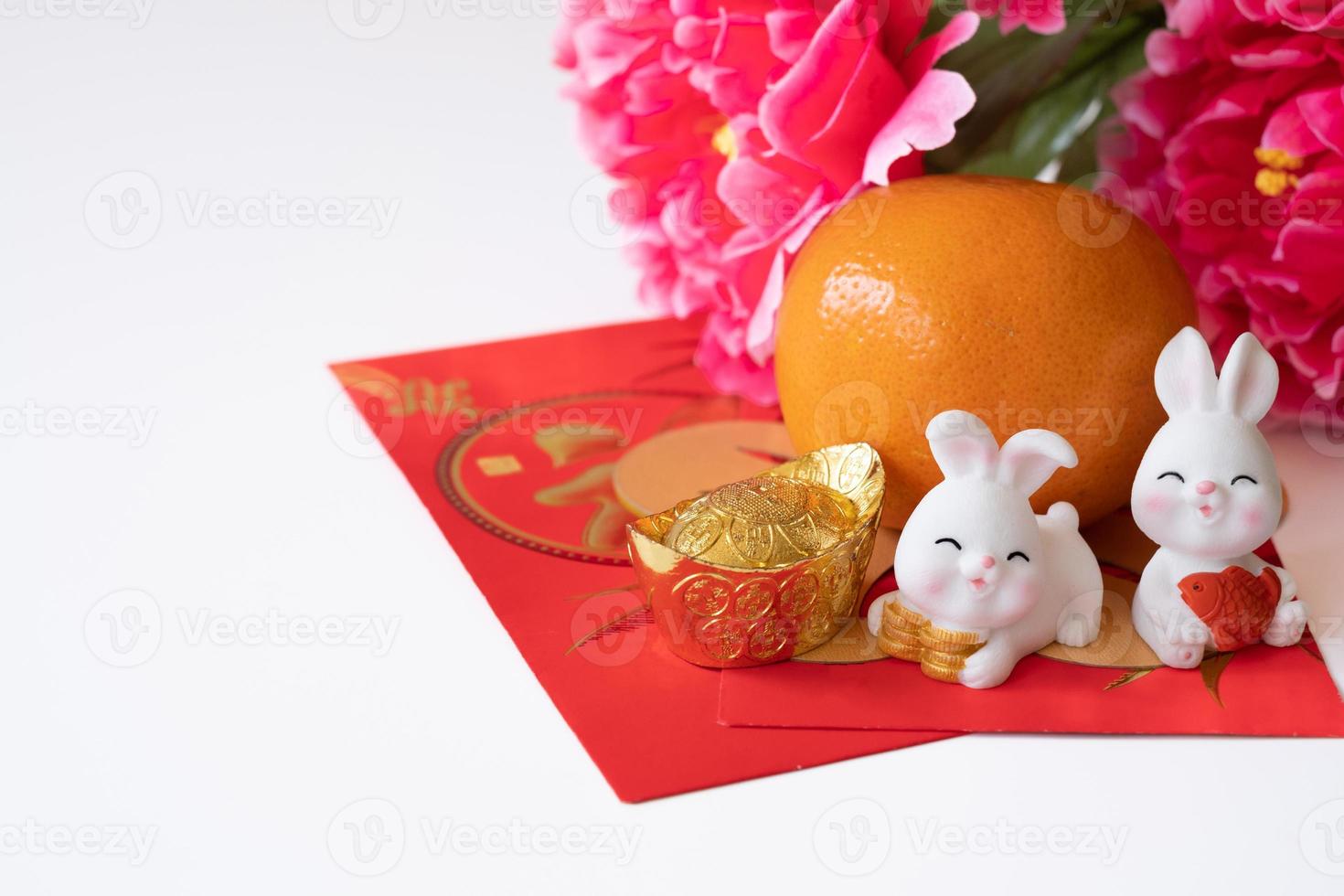 año nuevo chino del concepto del festival del conejo. naranja, sobres rojos, dos conejos y lingotes de oro decorados con flores de ciruela sobre fondo blanco. foto