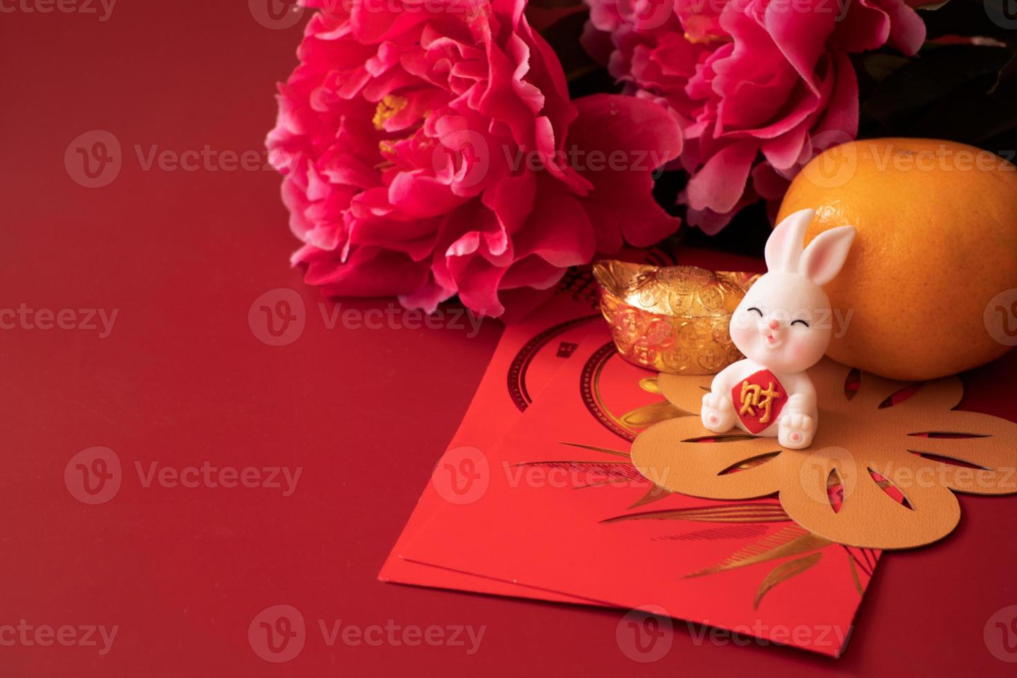 Chinese New Year of the rabbit festival concept. Mandarin orange, red envelopes, rabbit and gold ingot decorated with plum blossom on red background. photo