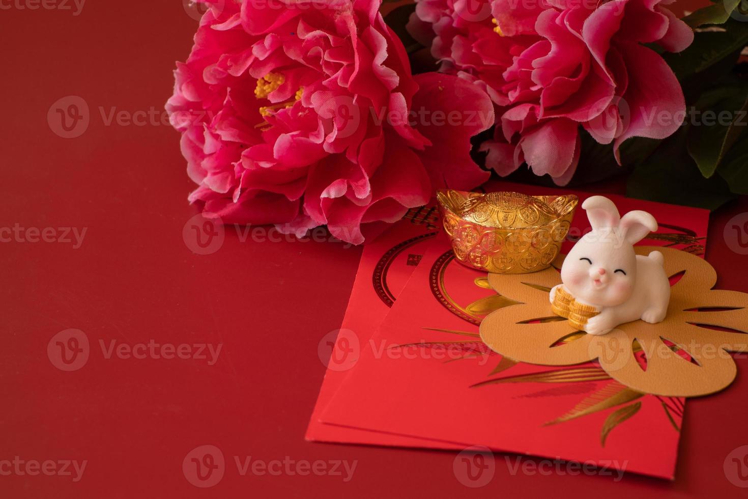 Chinese New Year of the rabbit festival concept. Mandarin orange, red envelopes, rabbit and gold ingot decorated with plum blossom on red background. photo