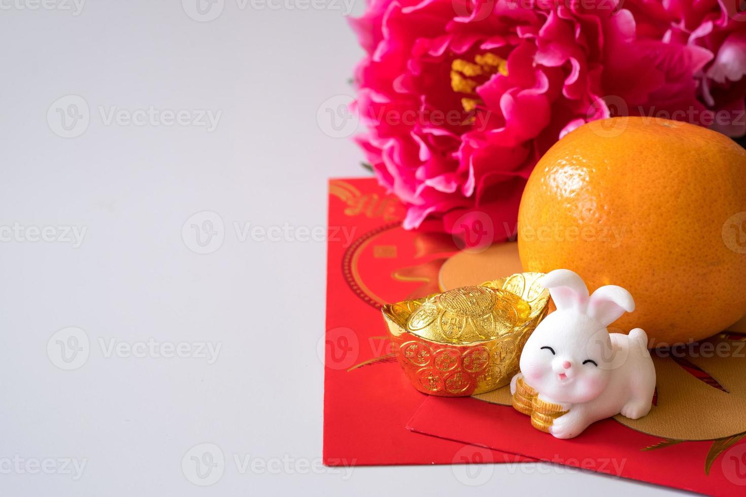 Chinese New Year of the rabbit festival concept. Orange, red envelopes, two rabbits and gold ingot decorated with plum blossom on white background. photo