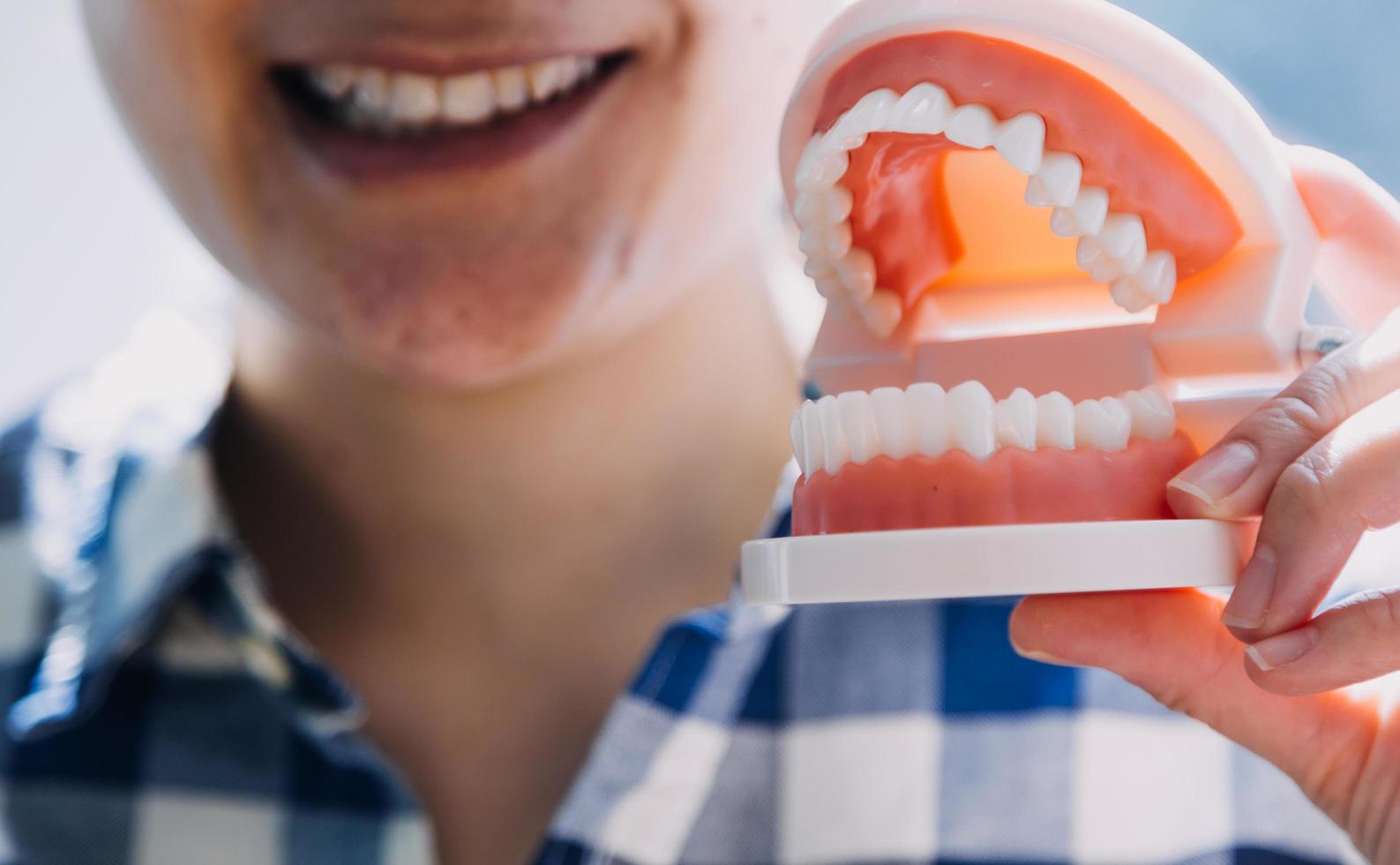 Stomatology concept, partial portrait of girl with strong white teeth looking at camera and smiling, fingers near face. Closeup of young woman at dentist's, studio, indoors photo