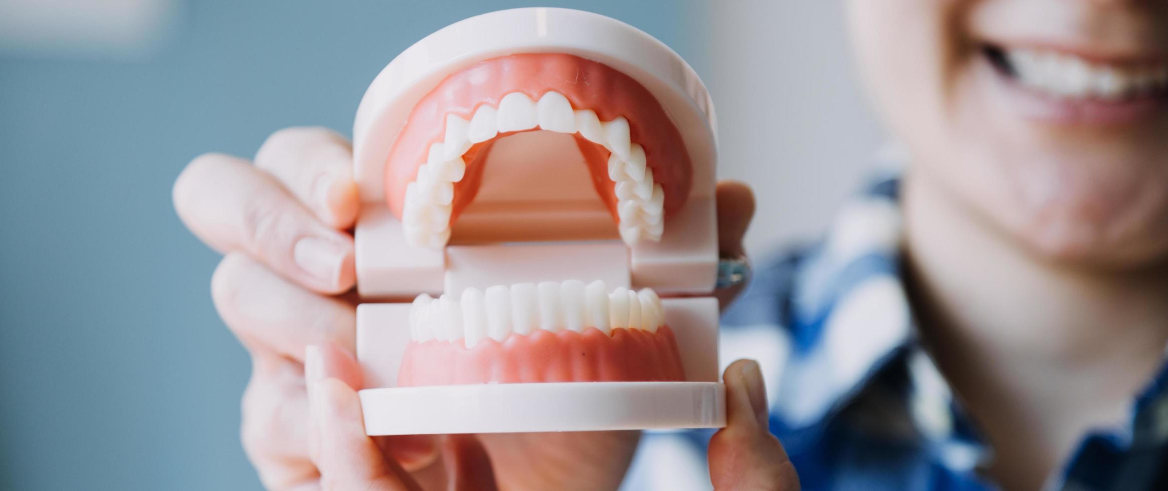 Stomatology concept, partial portrait of girl with strong white teeth looking at camera and smiling, fingers near face. Closeup of young woman at dentist's, studio, indoors photo