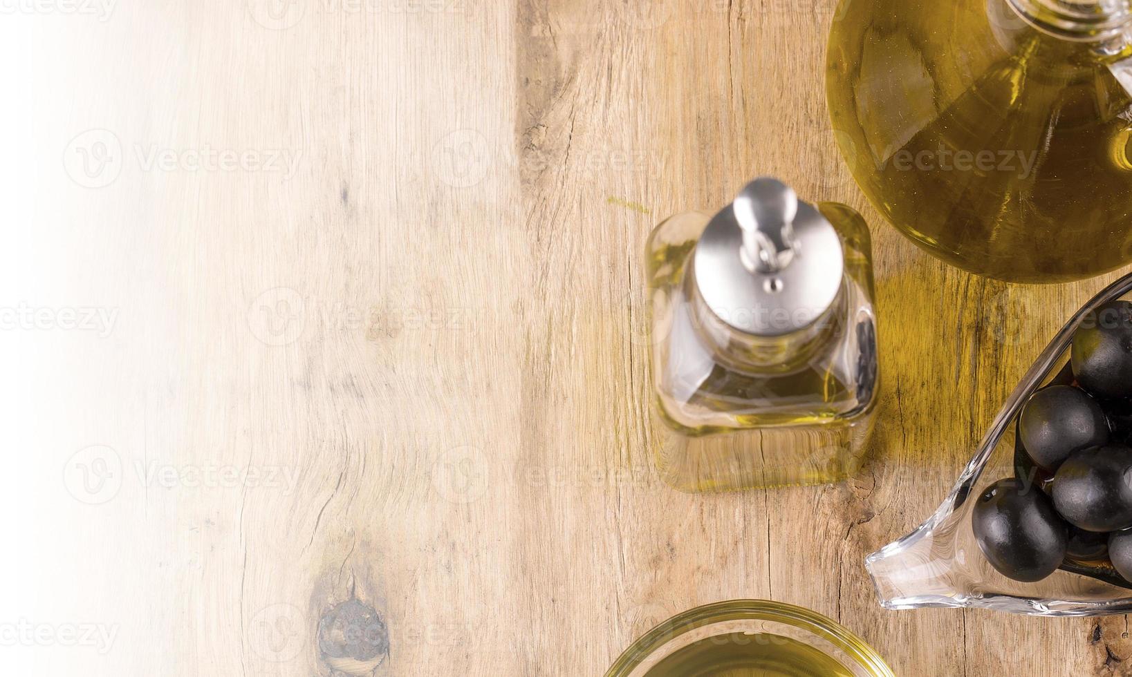 Olive oil with fresh herbs and Black olives on wooden photo