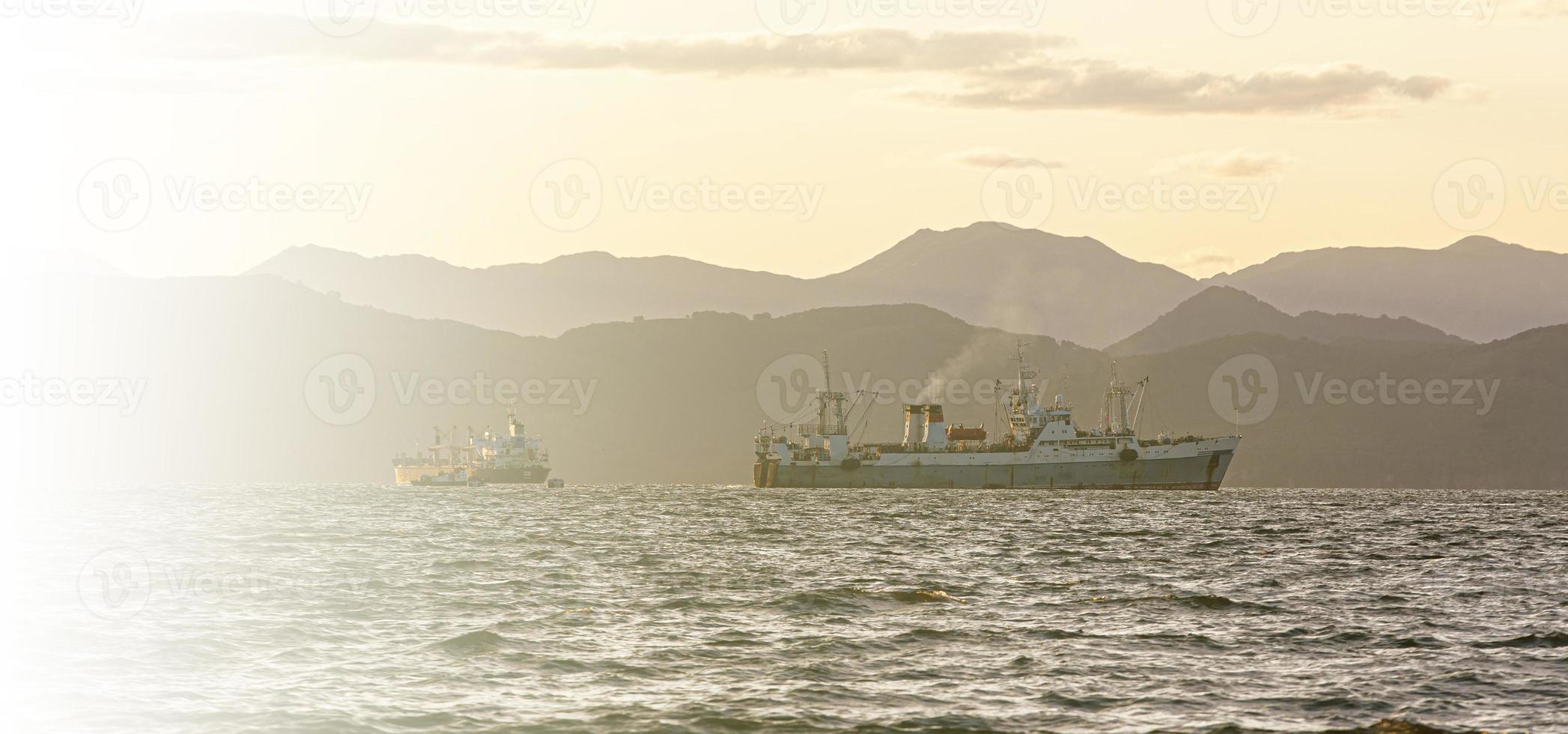 fishing ship in the sea at sunrise on the background of mountains photo