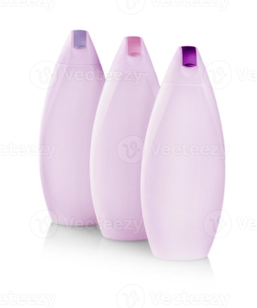 pink plastic bottles with colored capes of body care and beauty products. Studio photography of plastic bottle for shampoo - isolated on white background photo