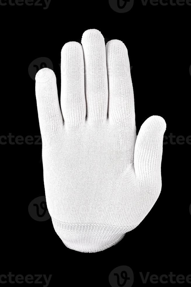 mano enguantada blanca sobre un fondo negro. una mano en un guante blanco muestra la señal de alto en un fondo negro foto