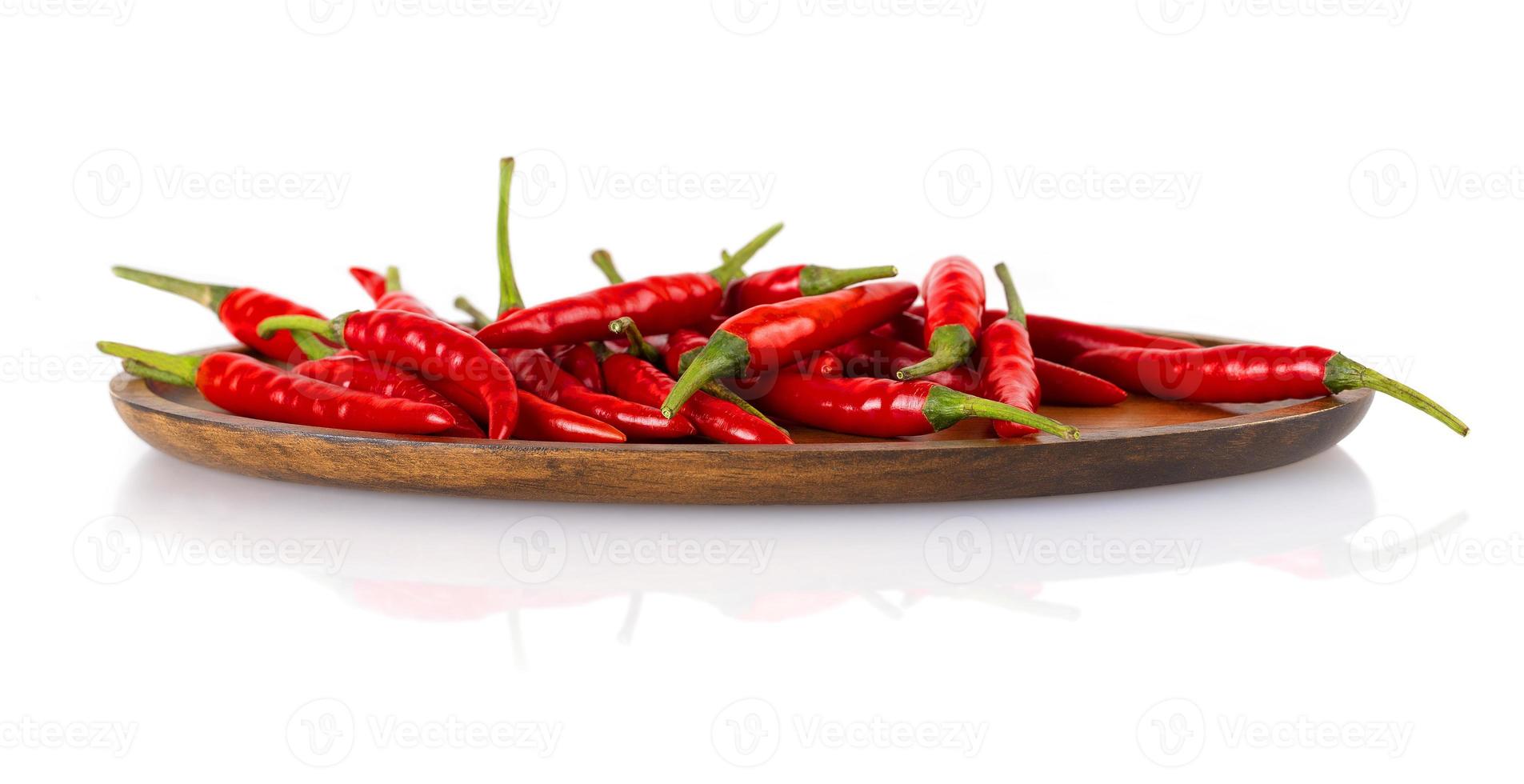 Red hot chili peppers on a wooden plate isolated on white background. photo