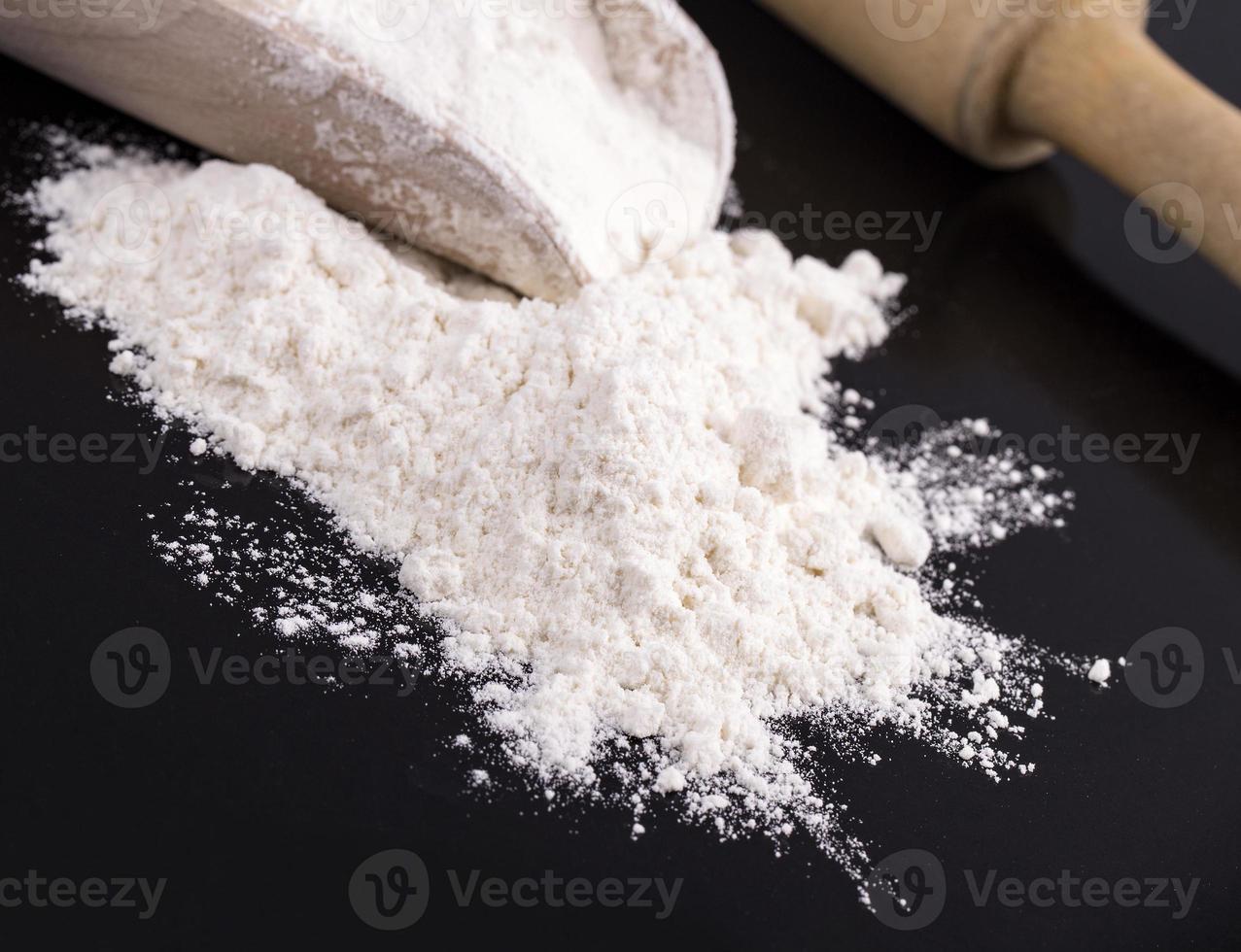 The white flour with a rolling pin on black photo