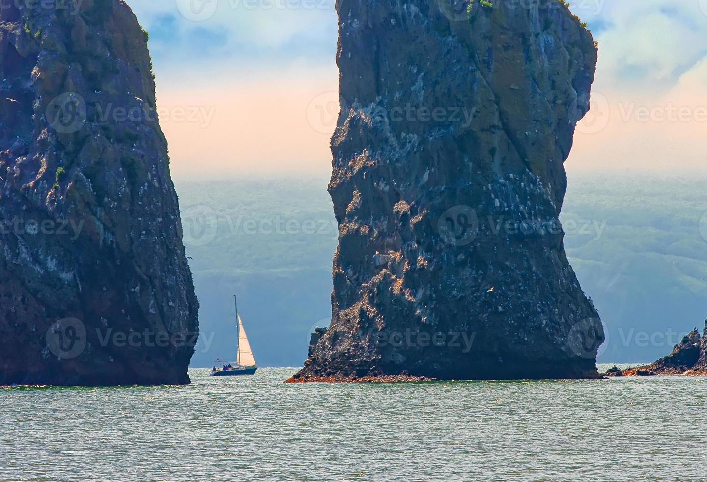 velero navega cerca de la costa y las rocas en la península de kamchatka foto