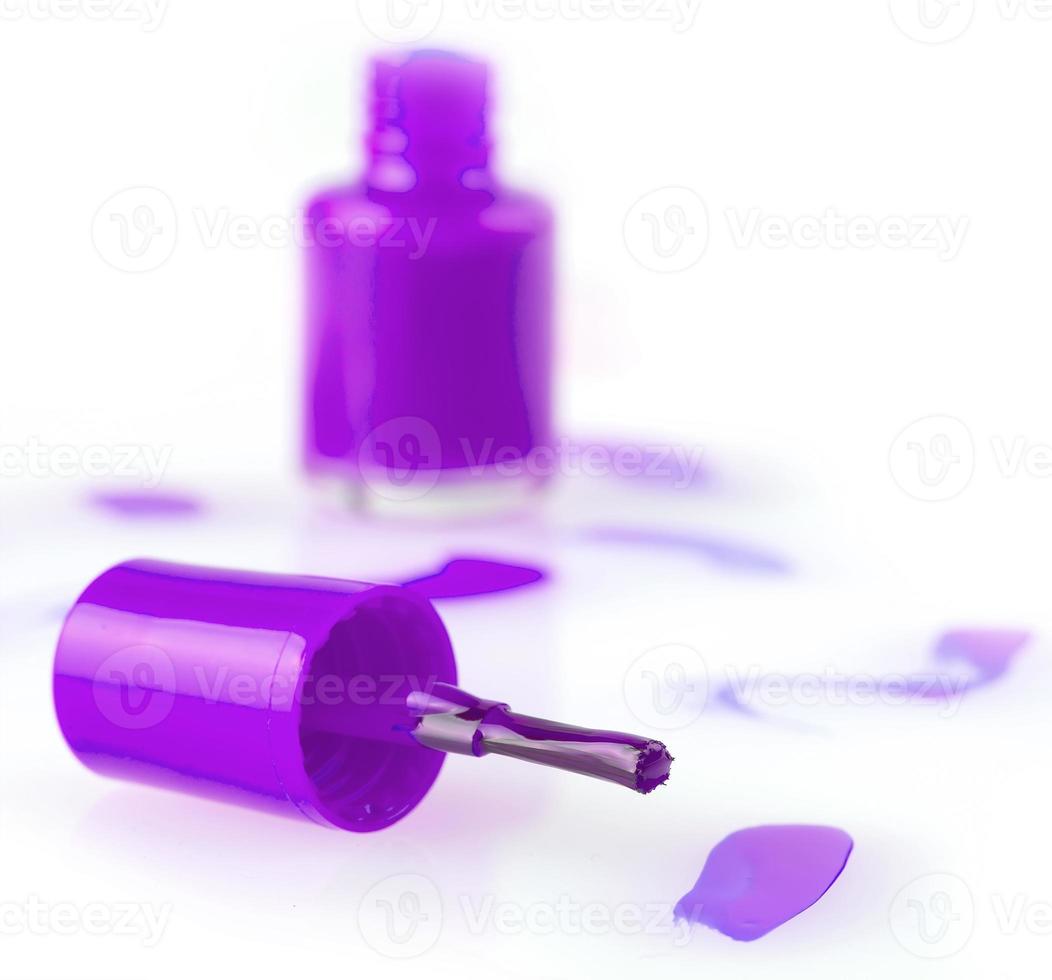 close up of a pink nail polish bottle and drop on white background. Selective focus photo