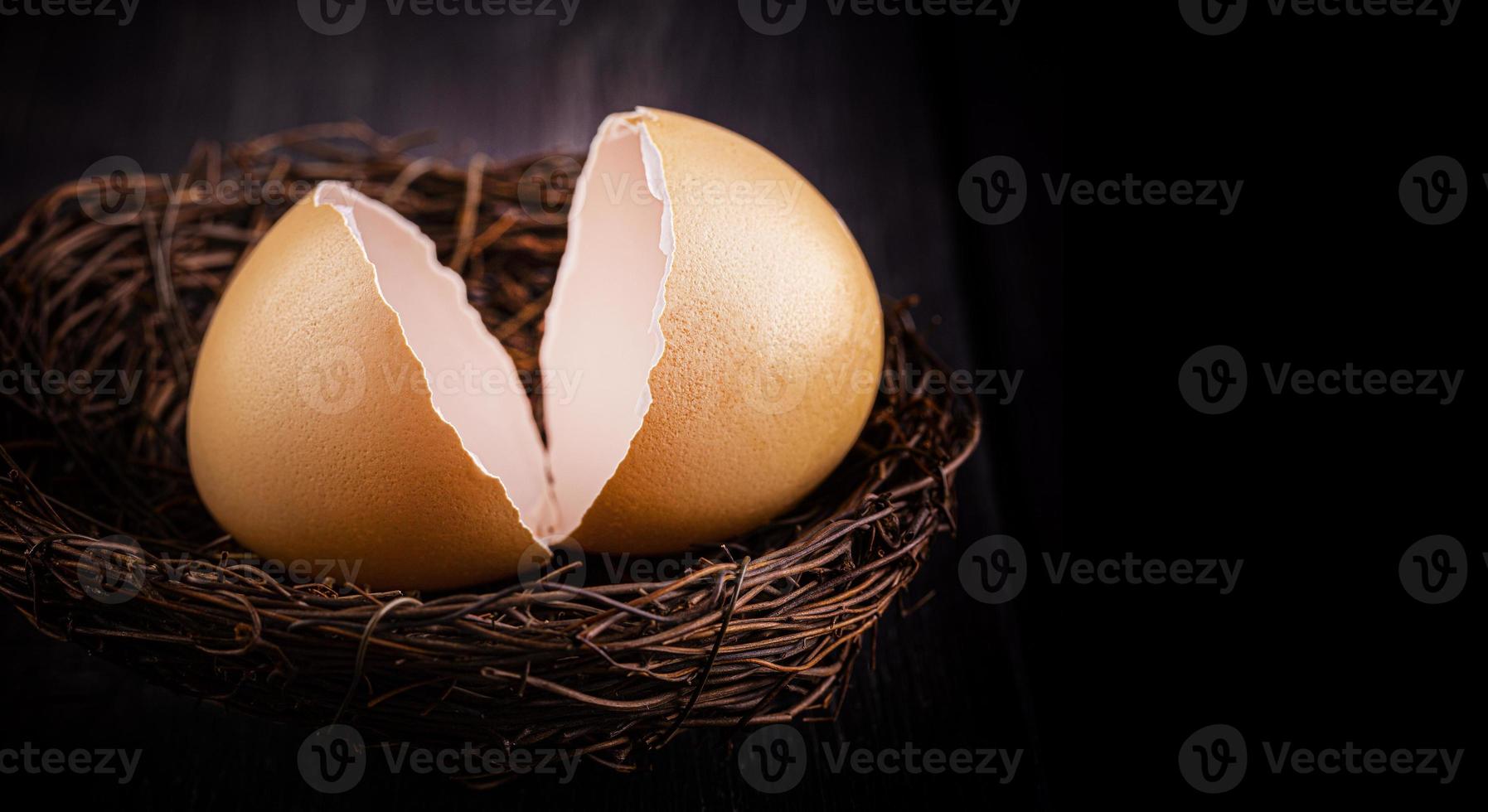 Selective focus. Brown broken egg shells in the nest on wooden surface photo