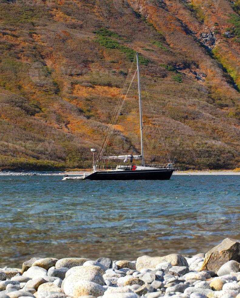 yacht on the bay of Pacific ocean in Kamchatka peninsula with mountains on background photo