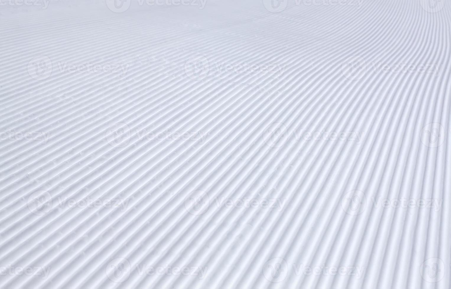 rolled and groomed ski slope, rilled snow background texture in winter photo