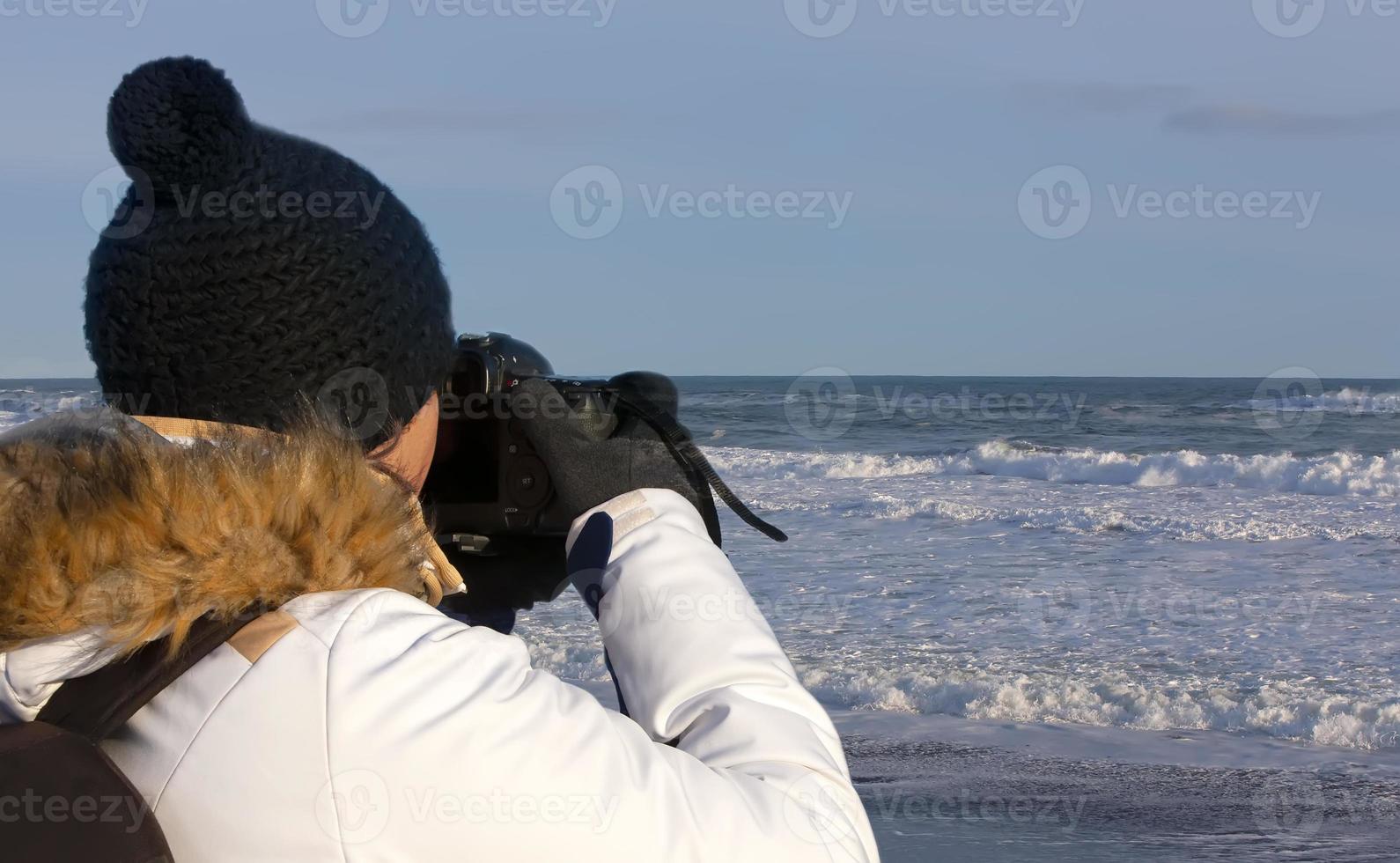 young woman photographing waves on Pacific ocean on Kamchatka Peninsula photo