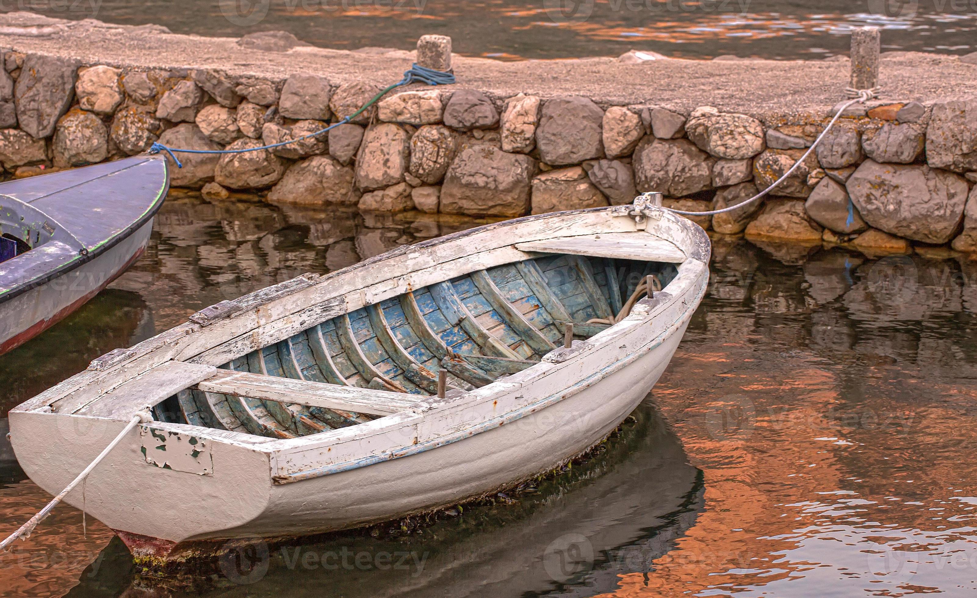 old white moored boat on sunset a river are ocean with rope and