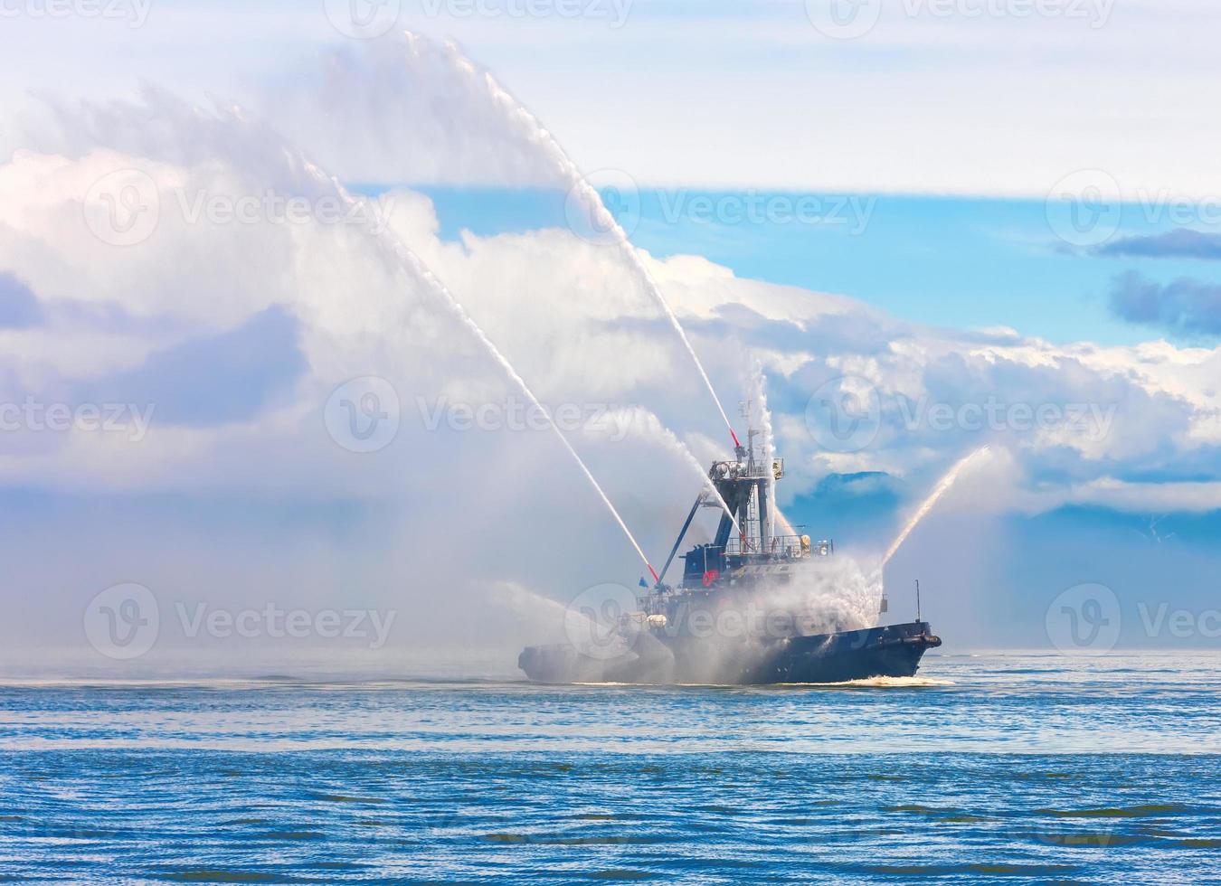 Floating tug boat is spraying jets of water photo