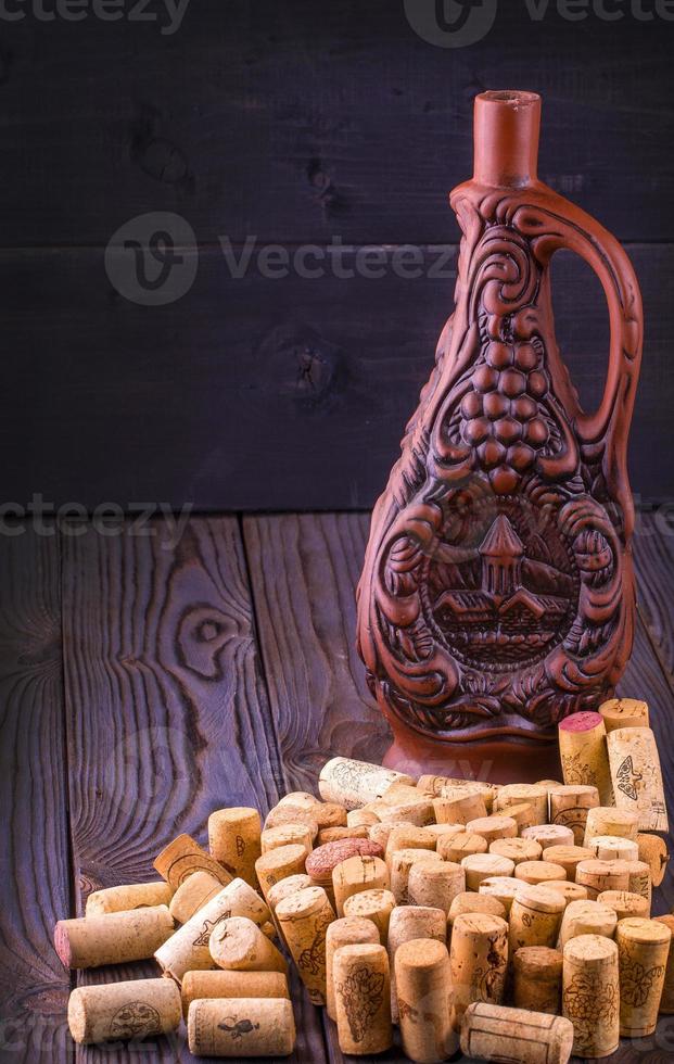 Clay bottle of wine and cork on a wooden table photo