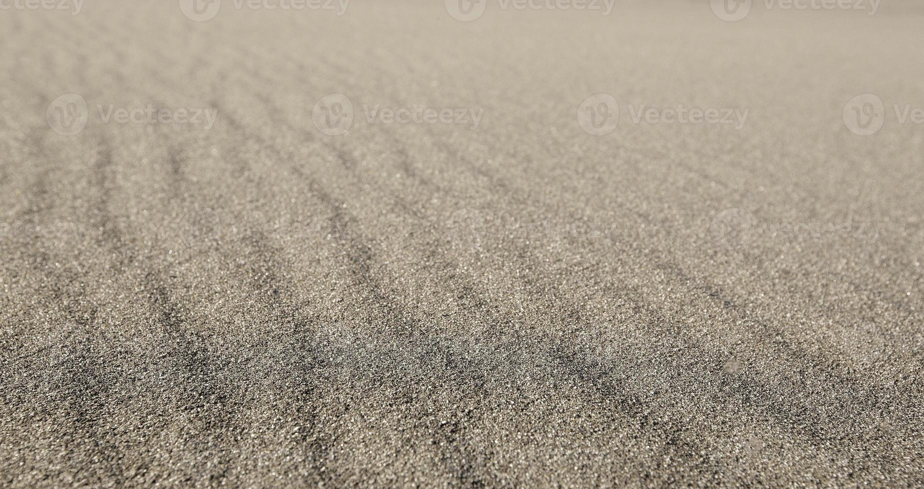 Textured wavy gray sand all over the frame. Selective focus photo