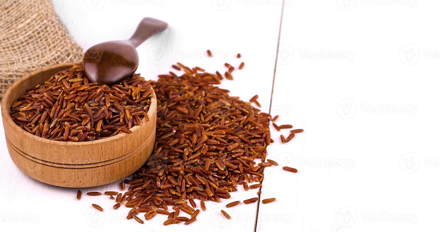 Dark rice, burlap and spoon in a wooden cup on a white dining table. photo