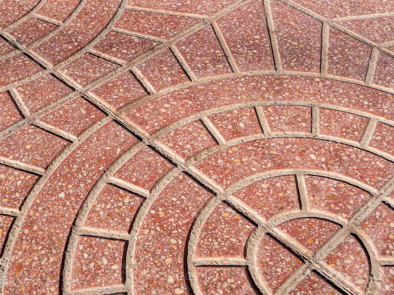 Diagonal view on a rounded pattern on a red stone pavement photo