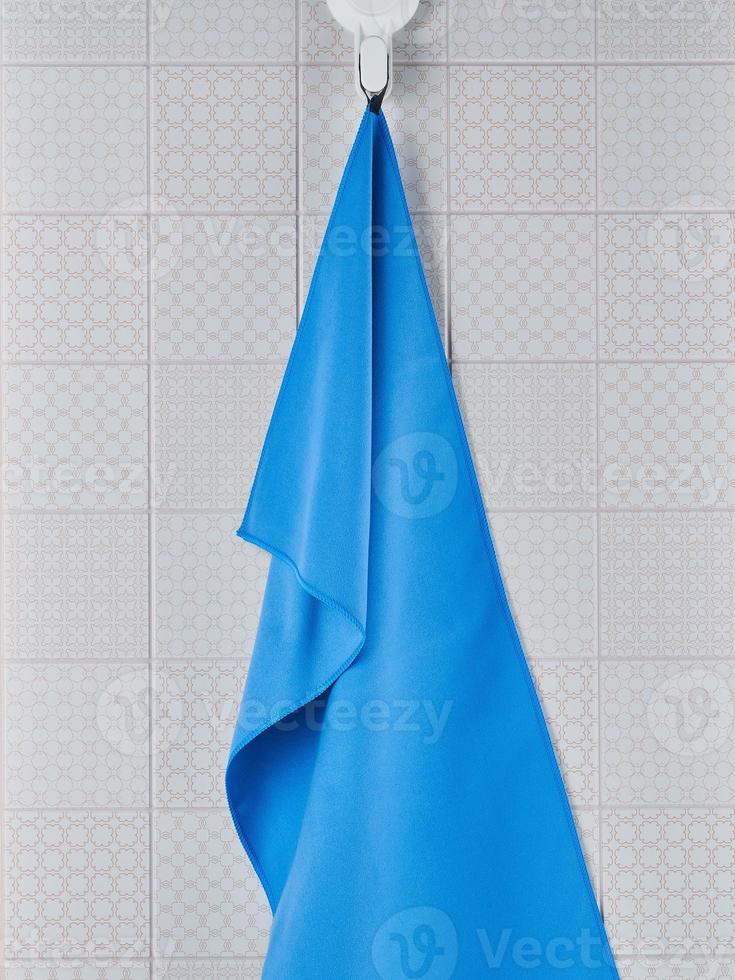 A bright blue kitchen towel is hanging on a hook on the kitchen wall photo