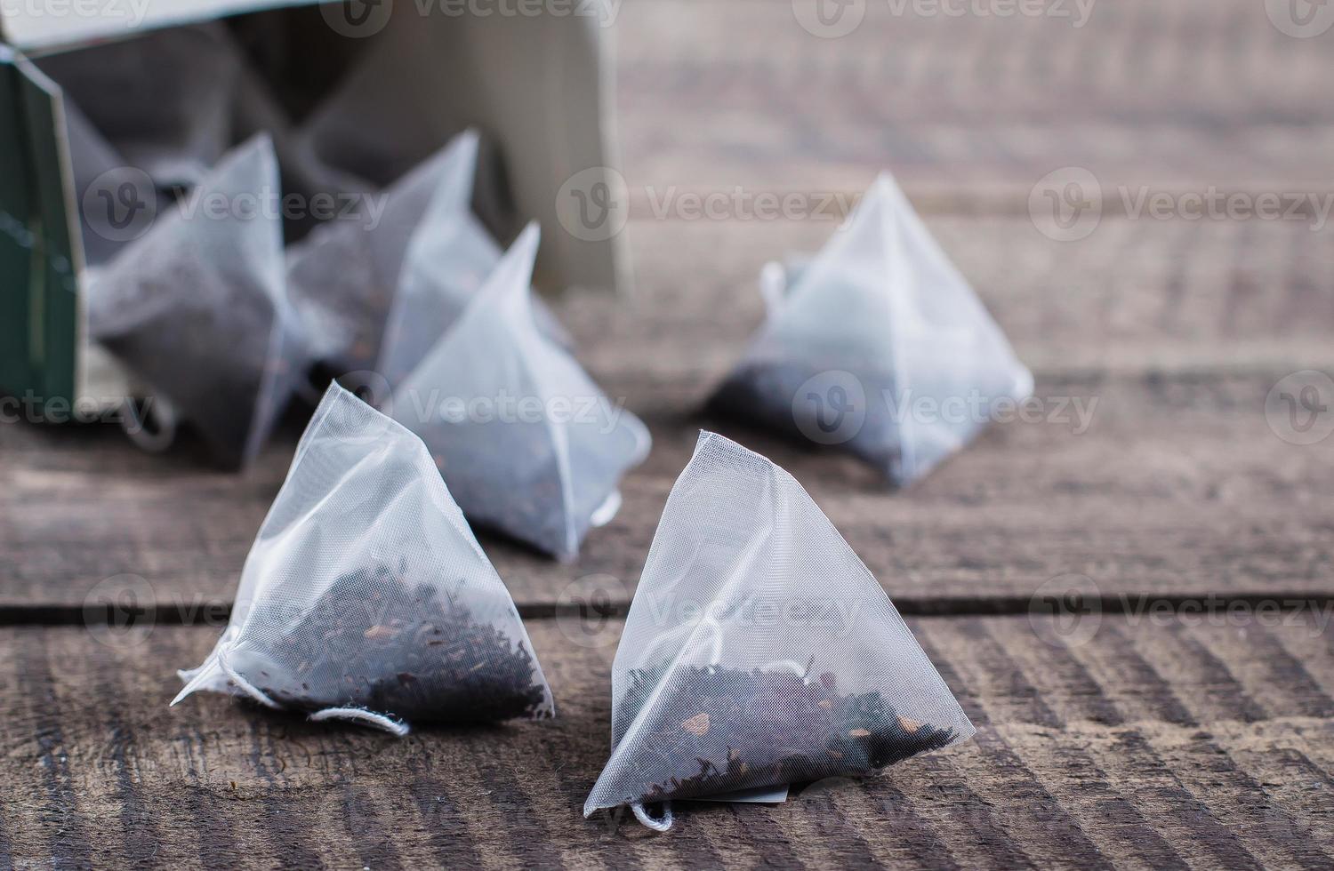 Tea bag shape of pyramid on wooden table background. Top view with copy space. photo