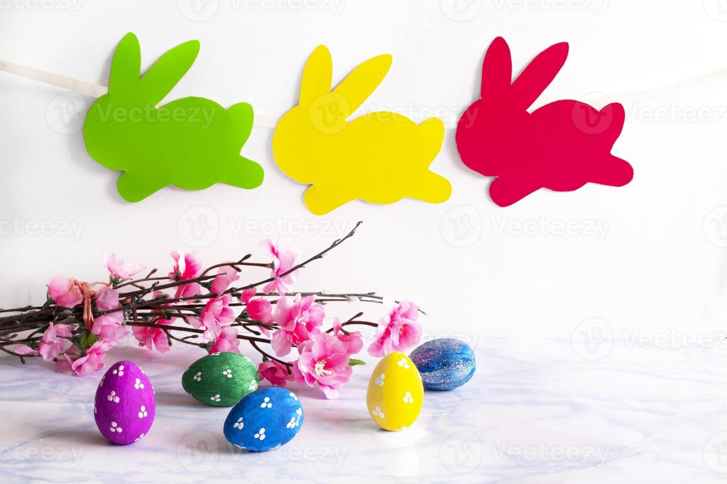 Colorful eggs with handmade bunny easter garland on netural background. photo