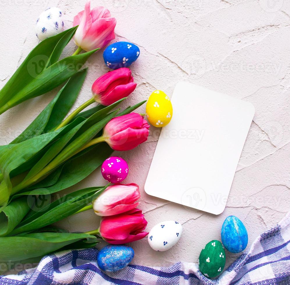 Happy ester. color eggs with tulips on grey background top view photo