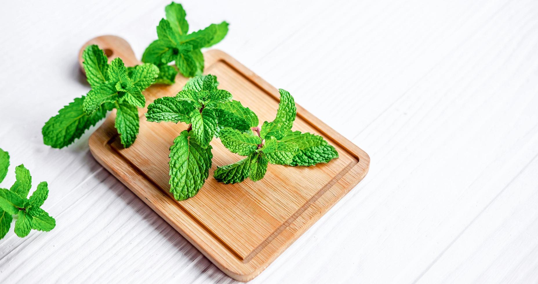 Mint leaf or Fresh mint on a wooden chopping board on white background photo