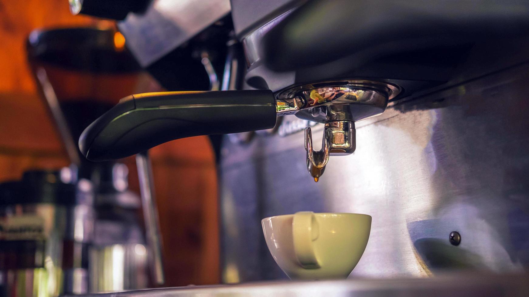 Coffee cup of espresso pouring from the coffee machine. Professional coffee brewing in the cafe photo