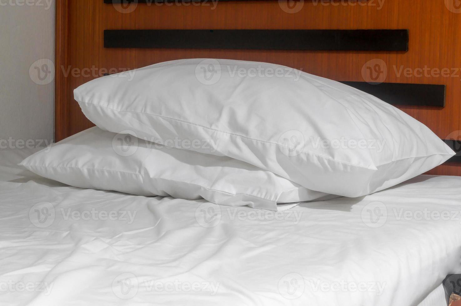 White untidy bed sheet and two pillows set on bed taken after guest' s use in resort or hotel room photo