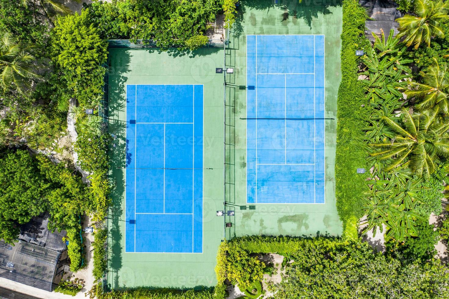 Amazing birds eye view of a tennis court surrounded by palm trees. Aerial tennis fields, outdoor sport and recreation concept photo