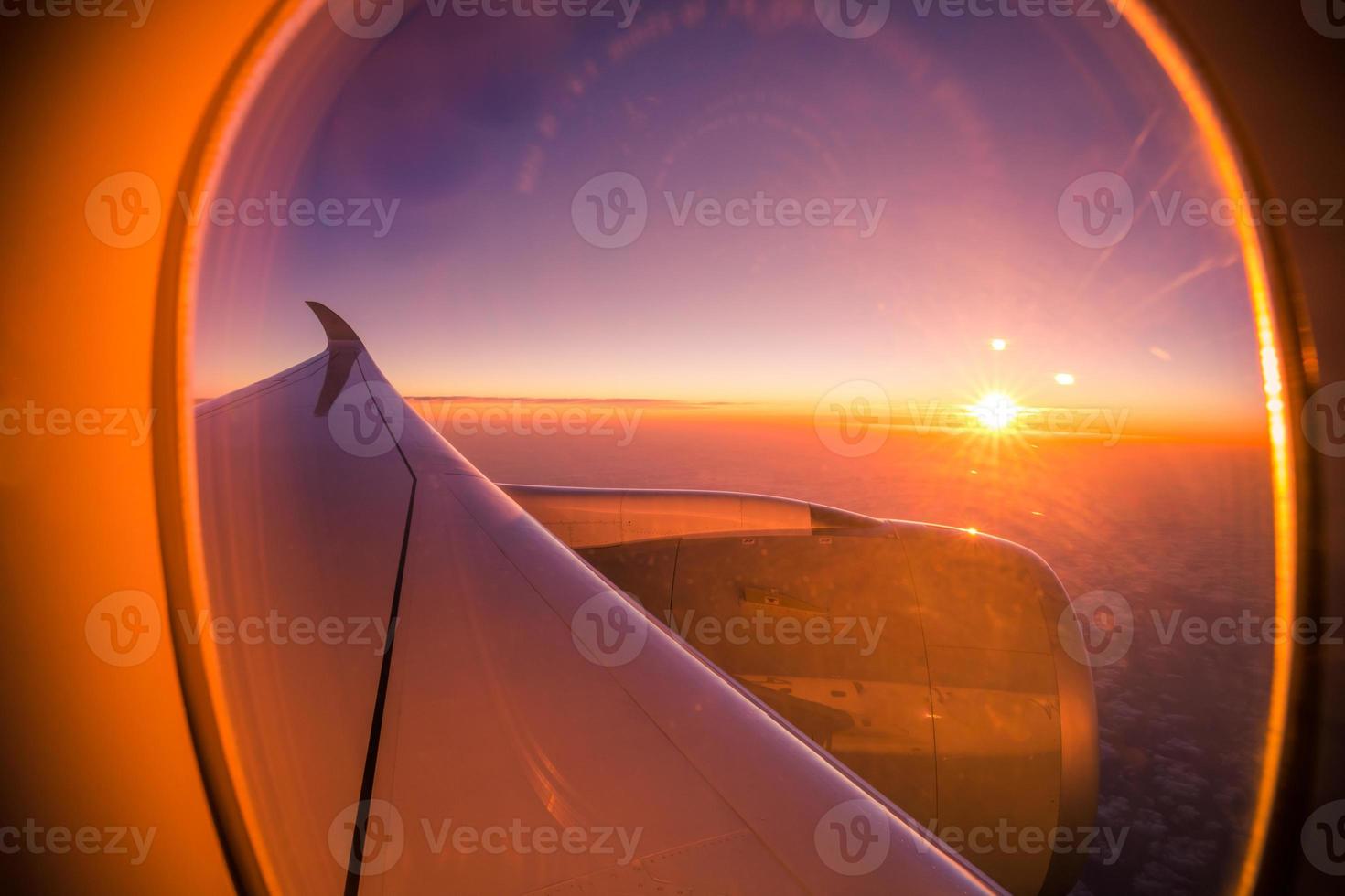 Beautiful sunset sunrise scenic view through the aircraft window with wings. Looking out window, travel background concept, airplane window with sun rays. Perfect aviation template photo