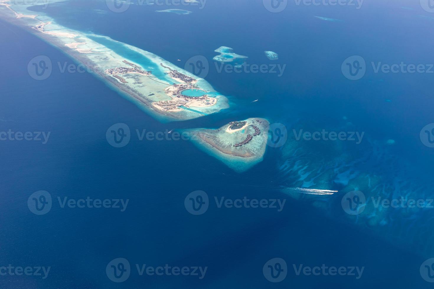 Aerial view of Maldives islands and atolls. Maldives tourism and travel background. Amazing blue sea, coral reef and atoll drone view. Beautiful nature landscape, seascape, exotic destination photo