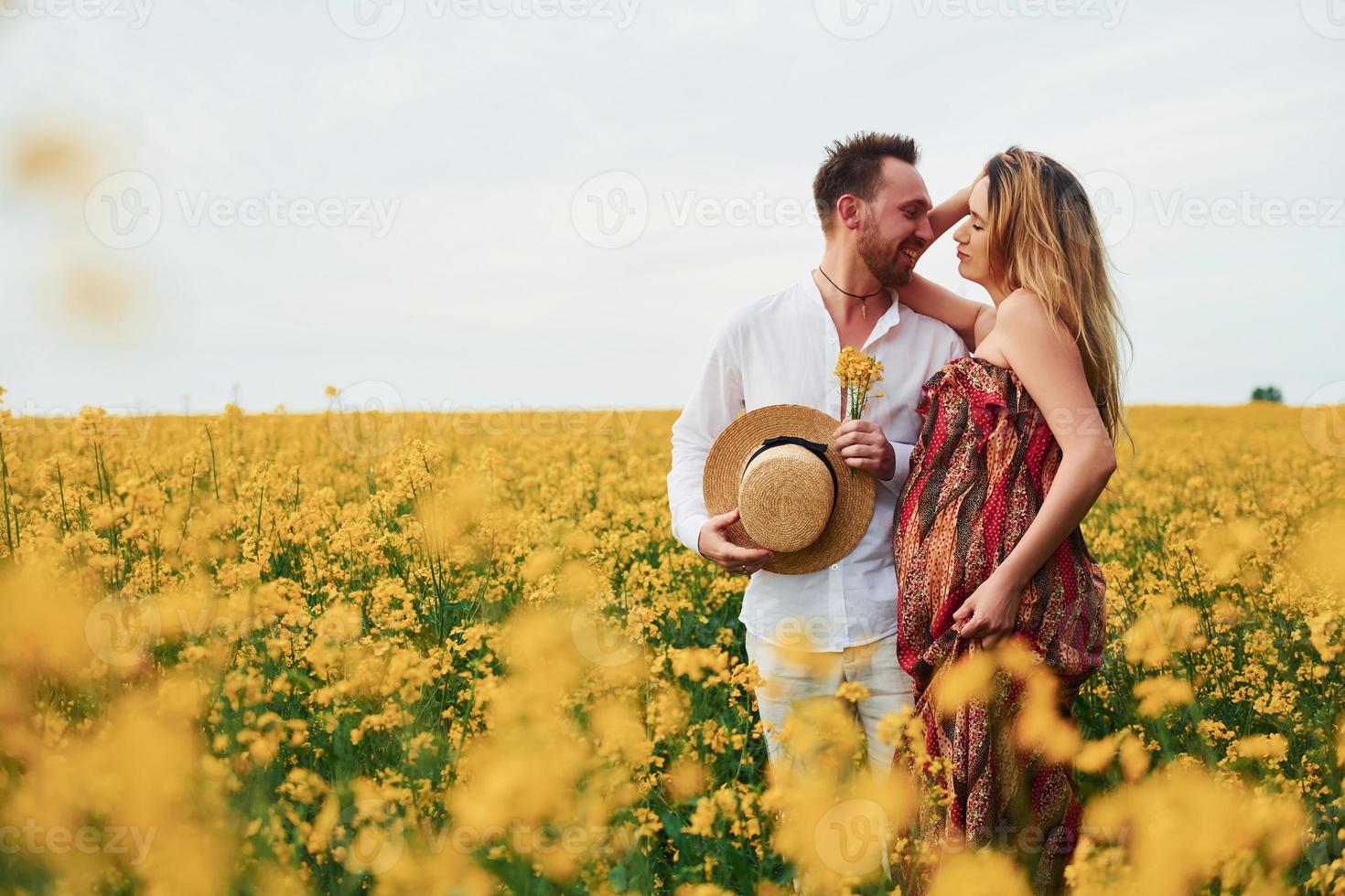 pareja embarazada por un campo de flores amarillas foto