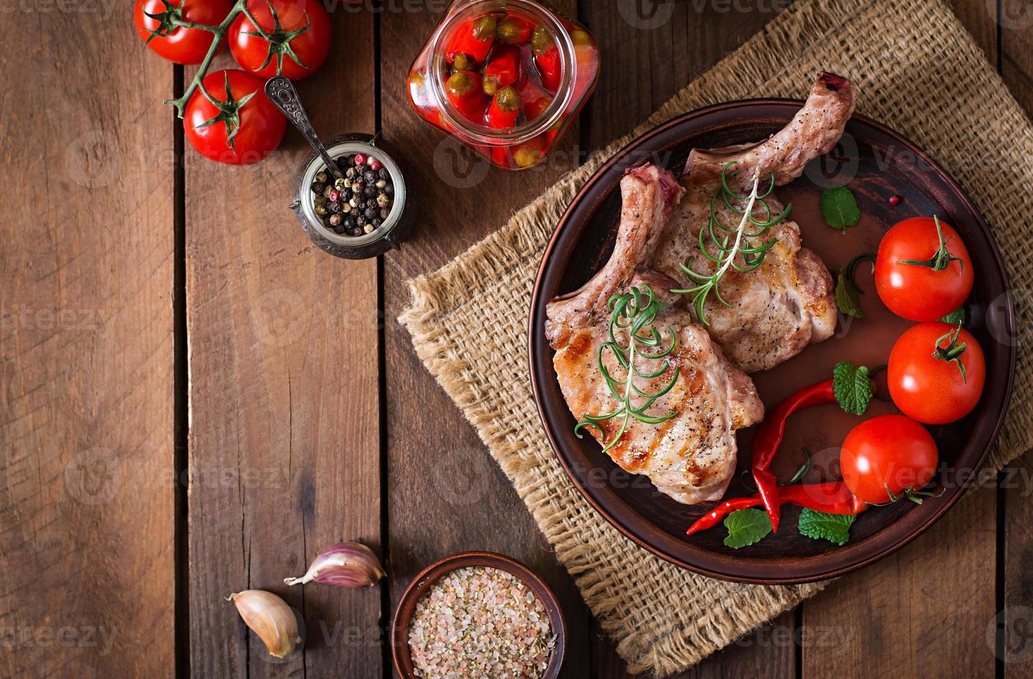 Grilled juicy steak on the bone with vegetables on a wooden background. Top view photo