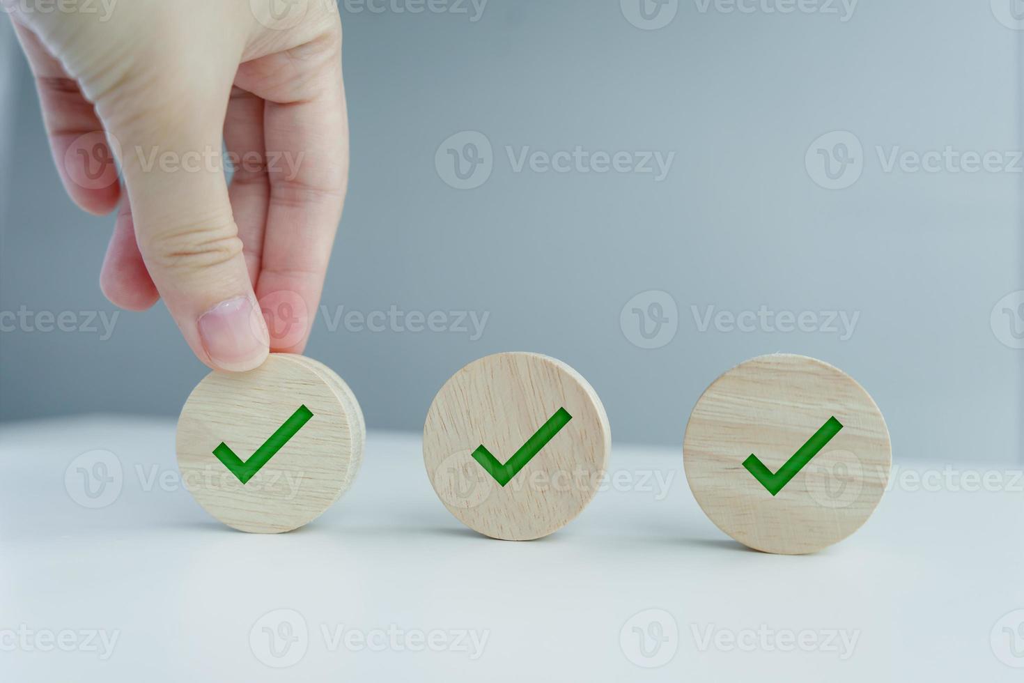 Checklist, Task list, Survey and assessment, Quality Control, Goals achievement and business success. To do list. Hand holding green check mark on wooden circle. photo