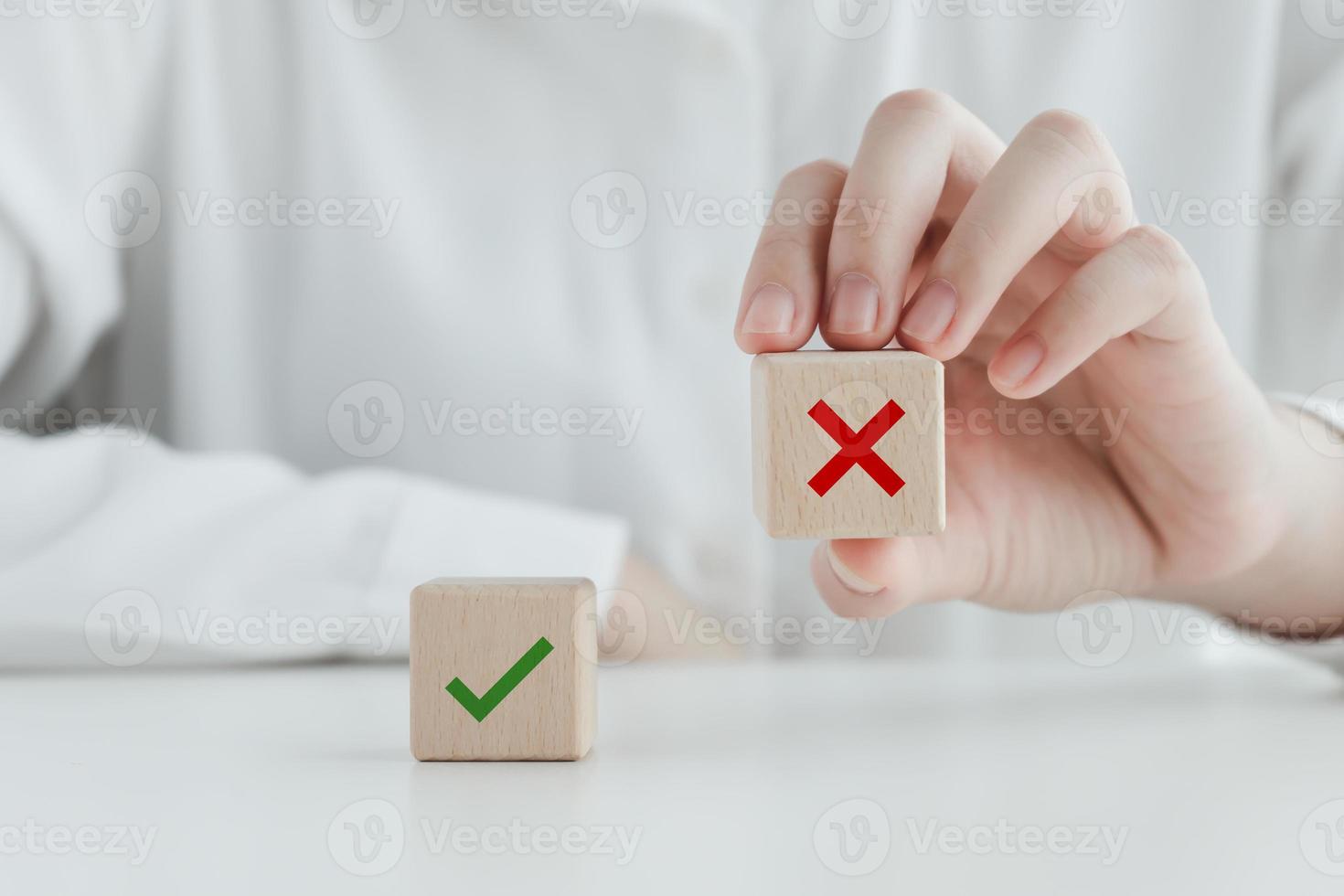 Human pick wrong or red cross icon on wood cube from green check mark for true or false mindset or elections vote, survey and assessment to change leader and transform quiz answer and poll concept. photo