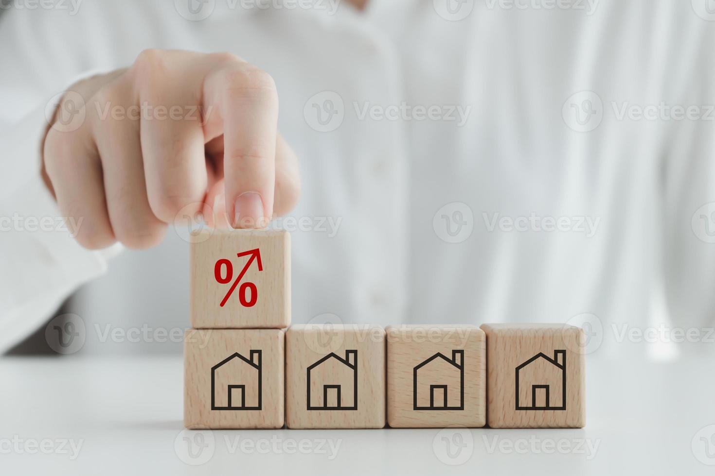 House, property investment, asset management concept. Interest rates increase, inflation, loan, mortgage, house tax, sale price. Hand touch red percentage sign icon on top of house icon on wood block. photo