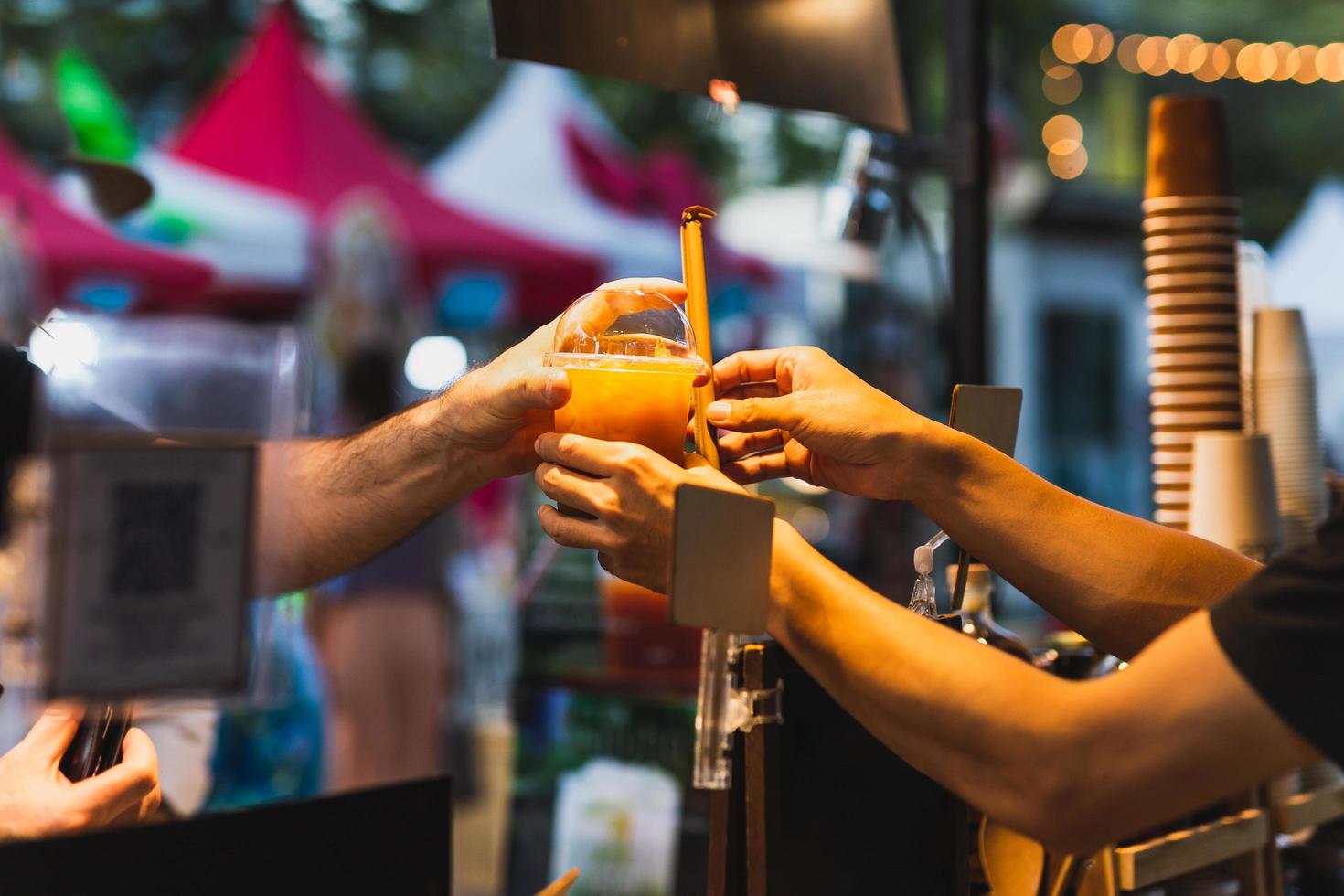 Male bartender serving healtyh drink to customer in plastic takeaway glass. photo