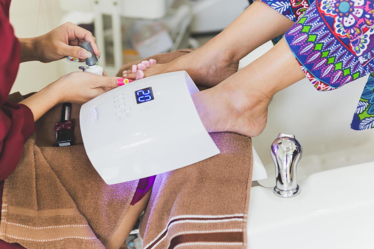 pie de mujer con pedicura bajo lámpara uv para secar el barniz. foto