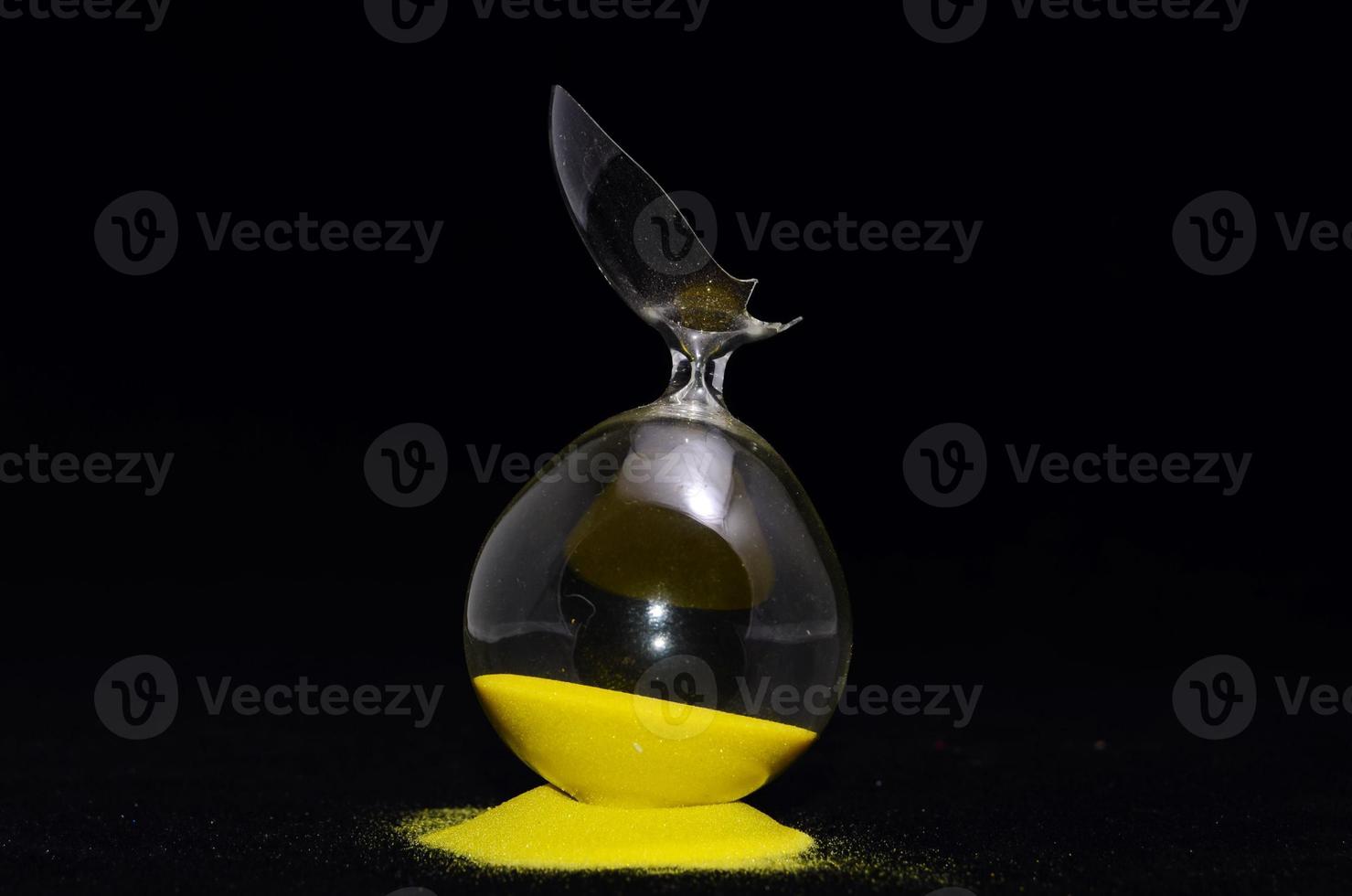 Broken hourglass on black background photo