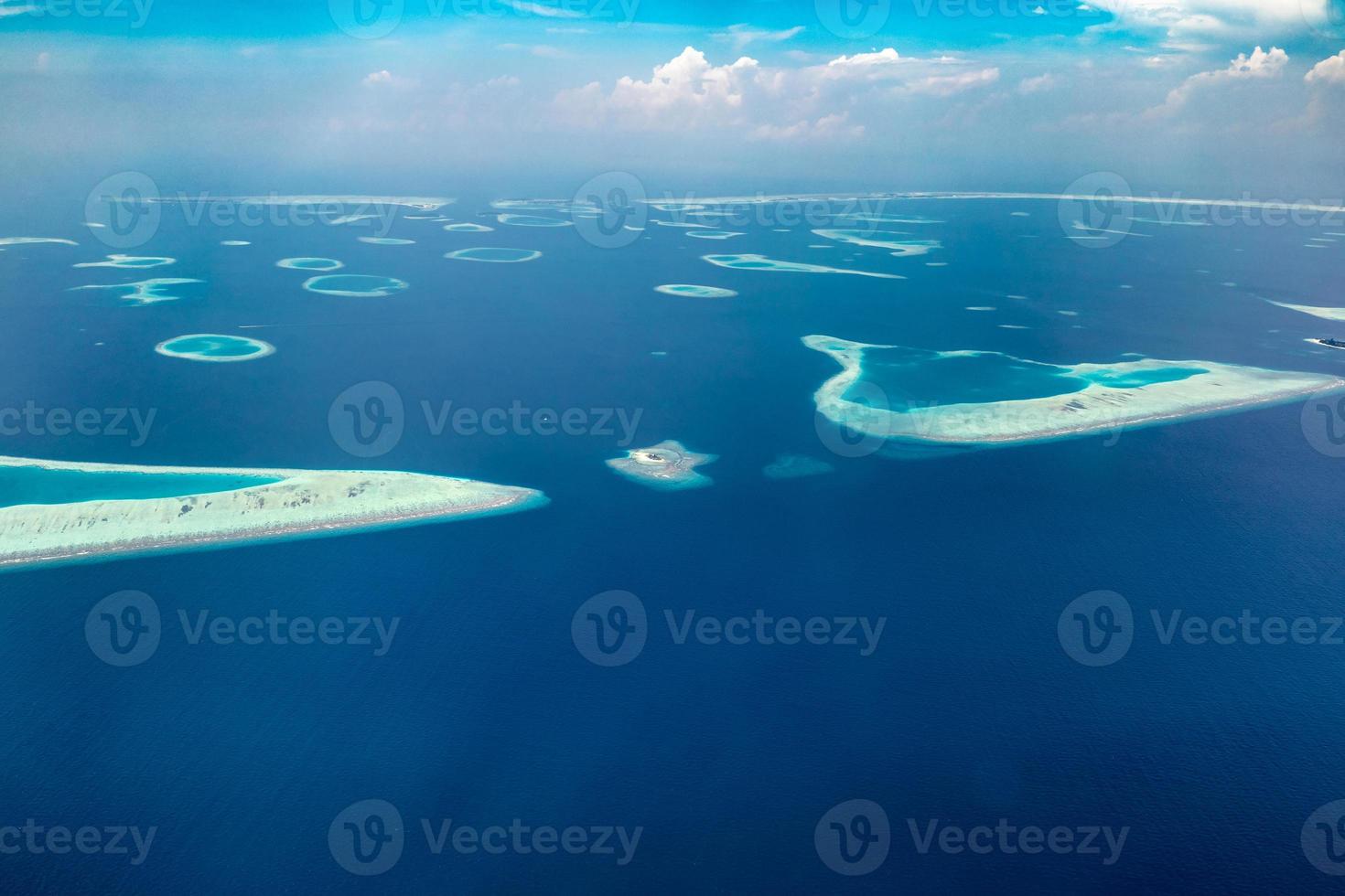 Aerial view of Maldives islands and atolls. Maldives tourism and travel background. Amazing blue sea, coral reef and atoll drone view. Beautiful nature landscape, seascape, exotic destination photo