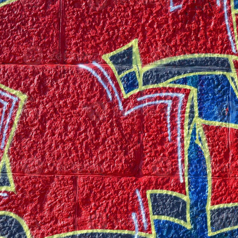 Fragment of graffiti drawings. The old wall decorated with paint stains in the style of street art culture. Colored background texture in warm tones photo