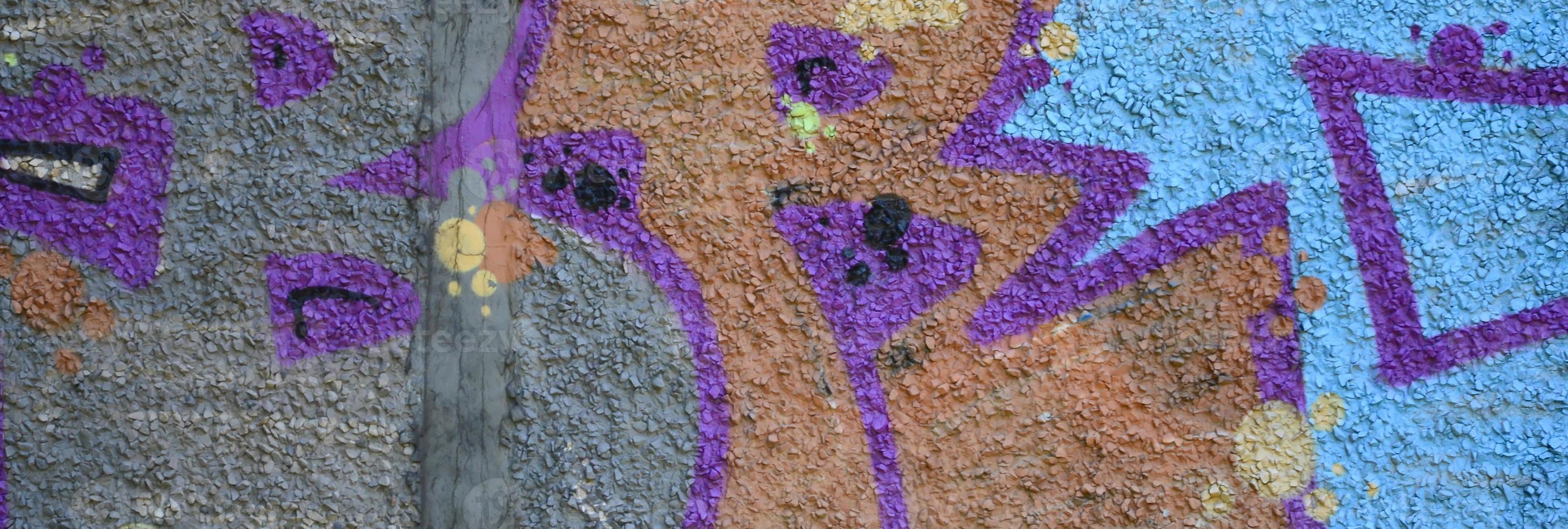Fragment of graffiti drawings. The old wall decorated with paint stains in the style of street art culture. Colored background texture in warm tones photo