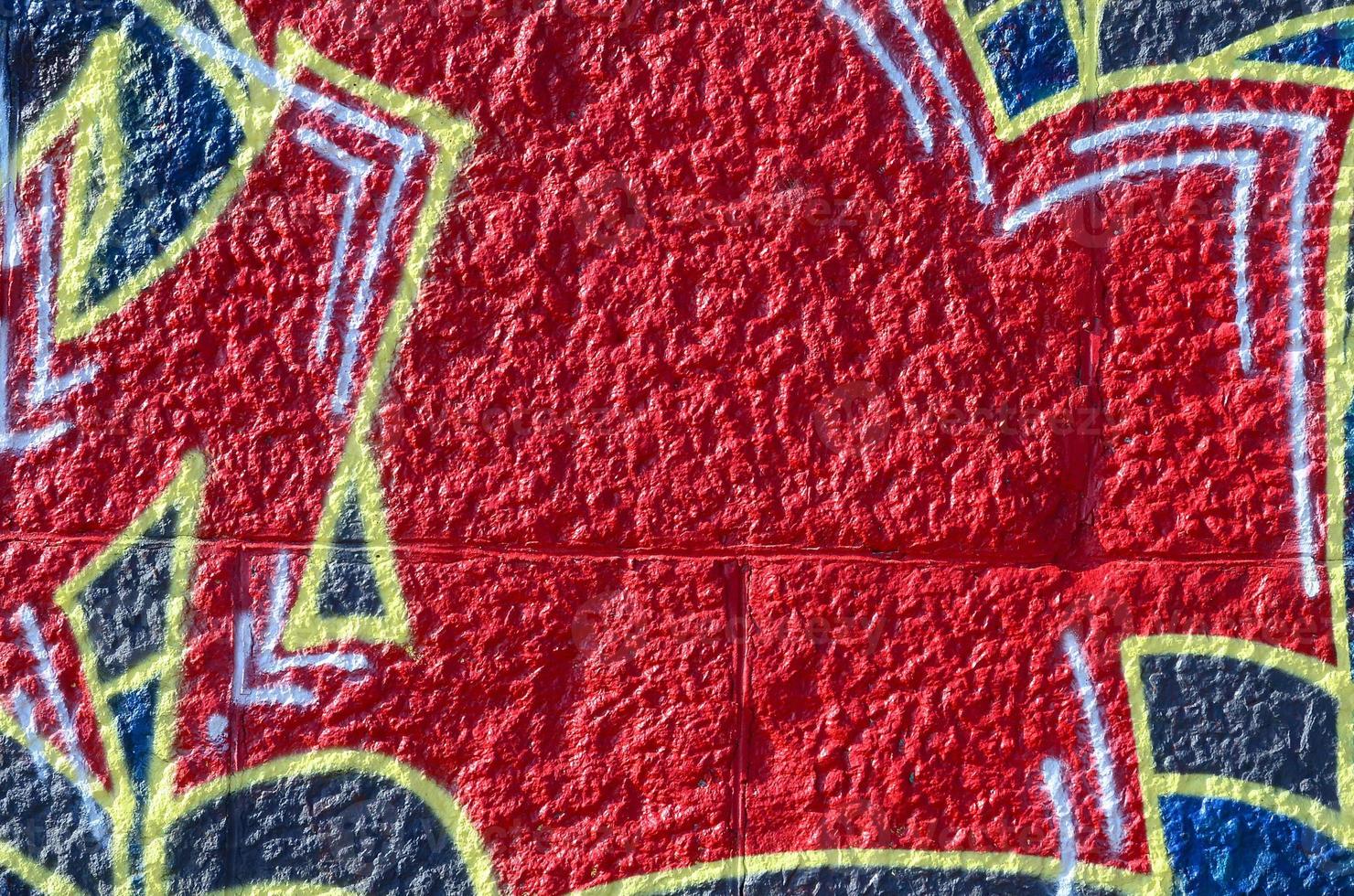 Fragment of graffiti drawings. The old wall decorated with paint stains in the style of street art culture. Colored background texture in warm tones photo