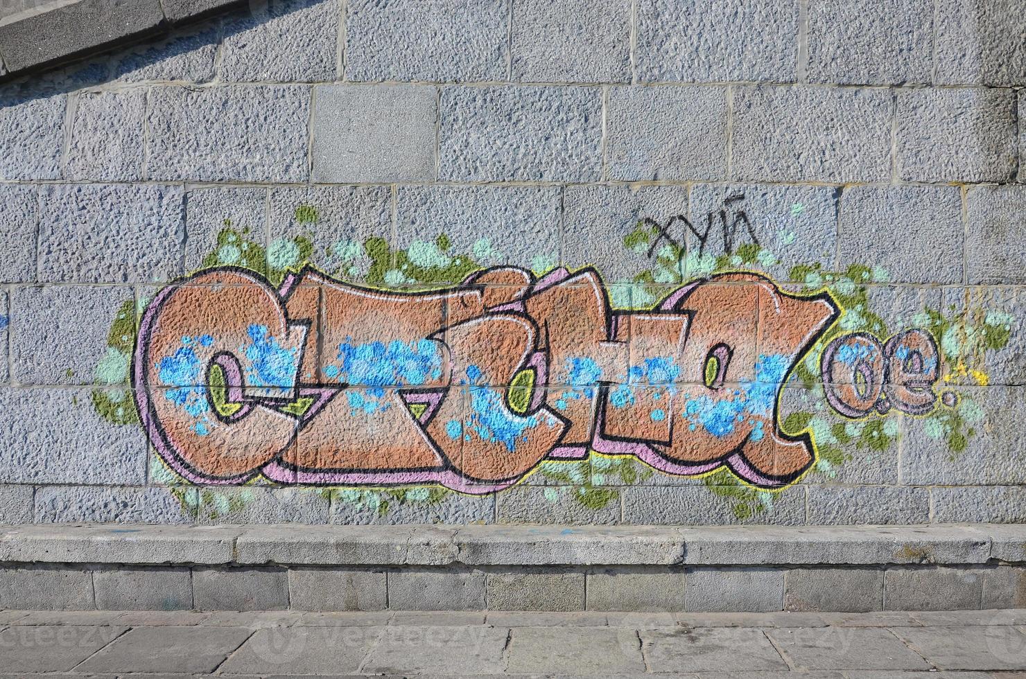 Fragment of graffiti drawings. The old wall decorated with paint stains in the style of street art culture. Colored background texture in warm tones photo