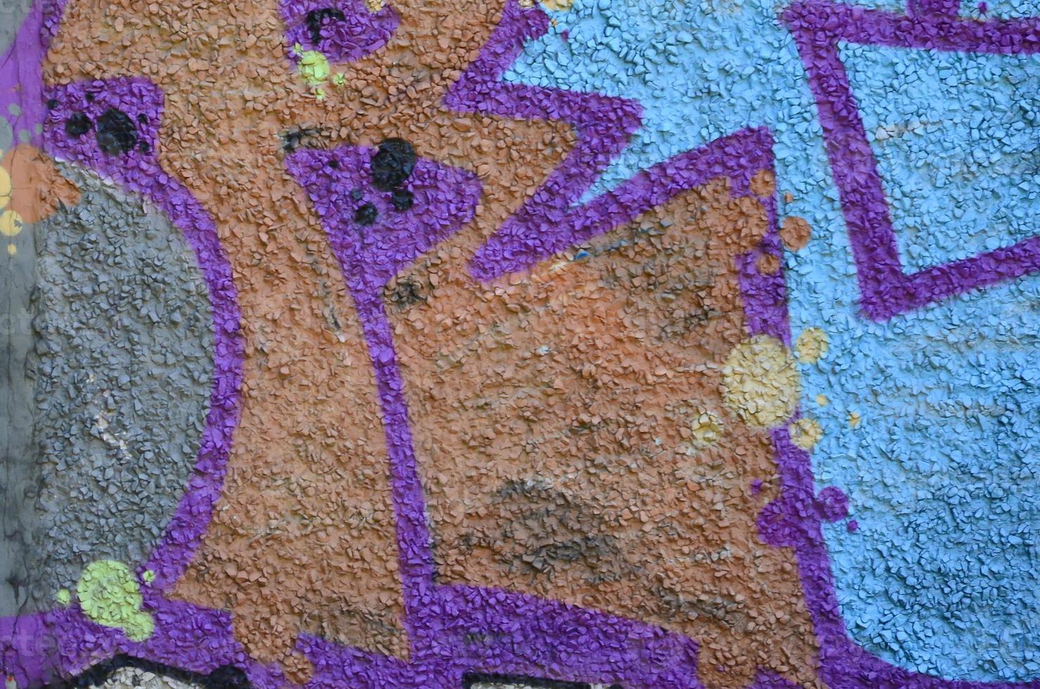 Fragment of graffiti drawings. The old wall decorated with paint stains in the style of street art culture. Colored background texture in warm tones photo