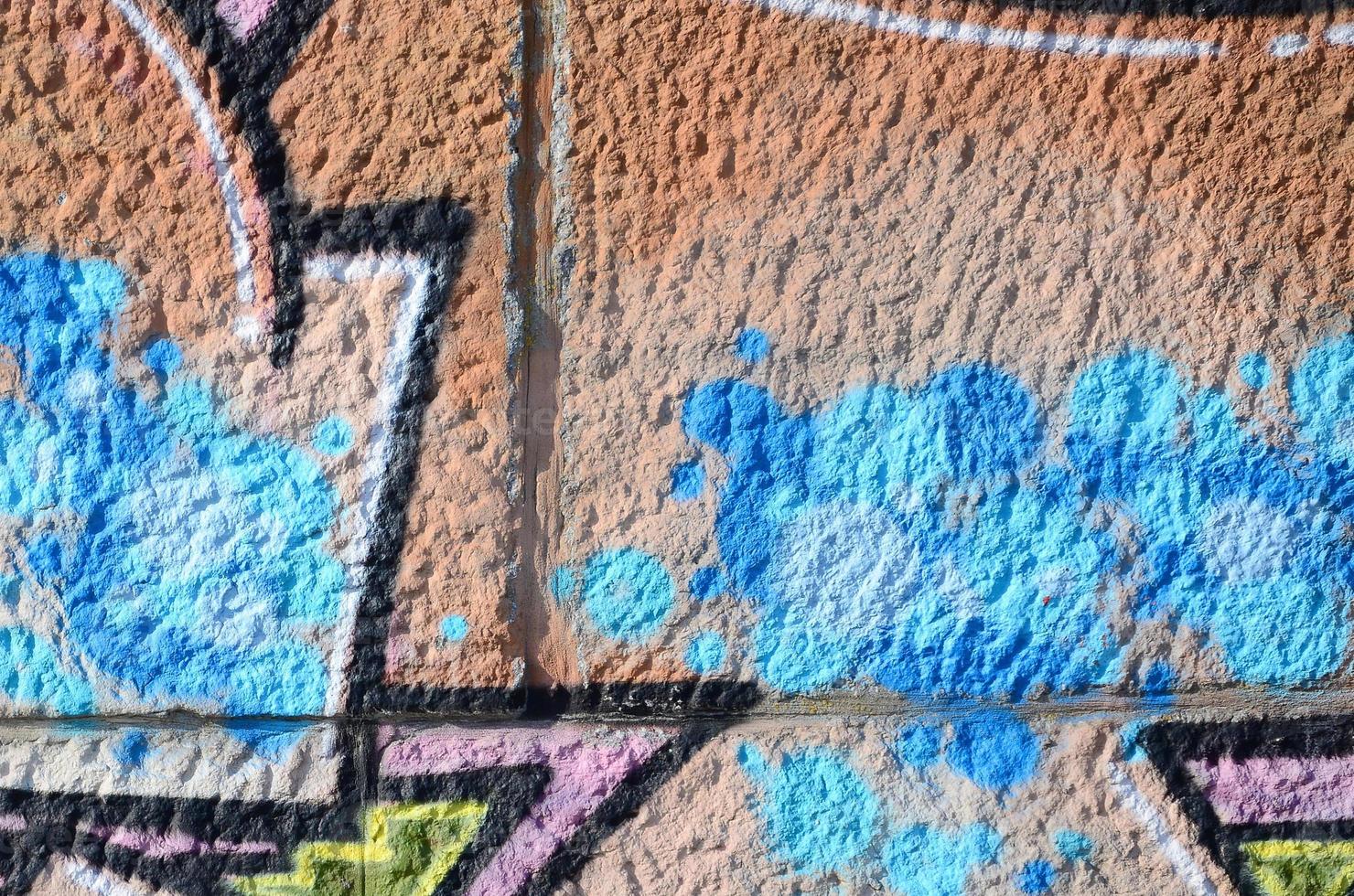 Fragment of graffiti drawings. The old wall decorated with paint stains in the style of street art culture. Colored background texture in warm tones photo