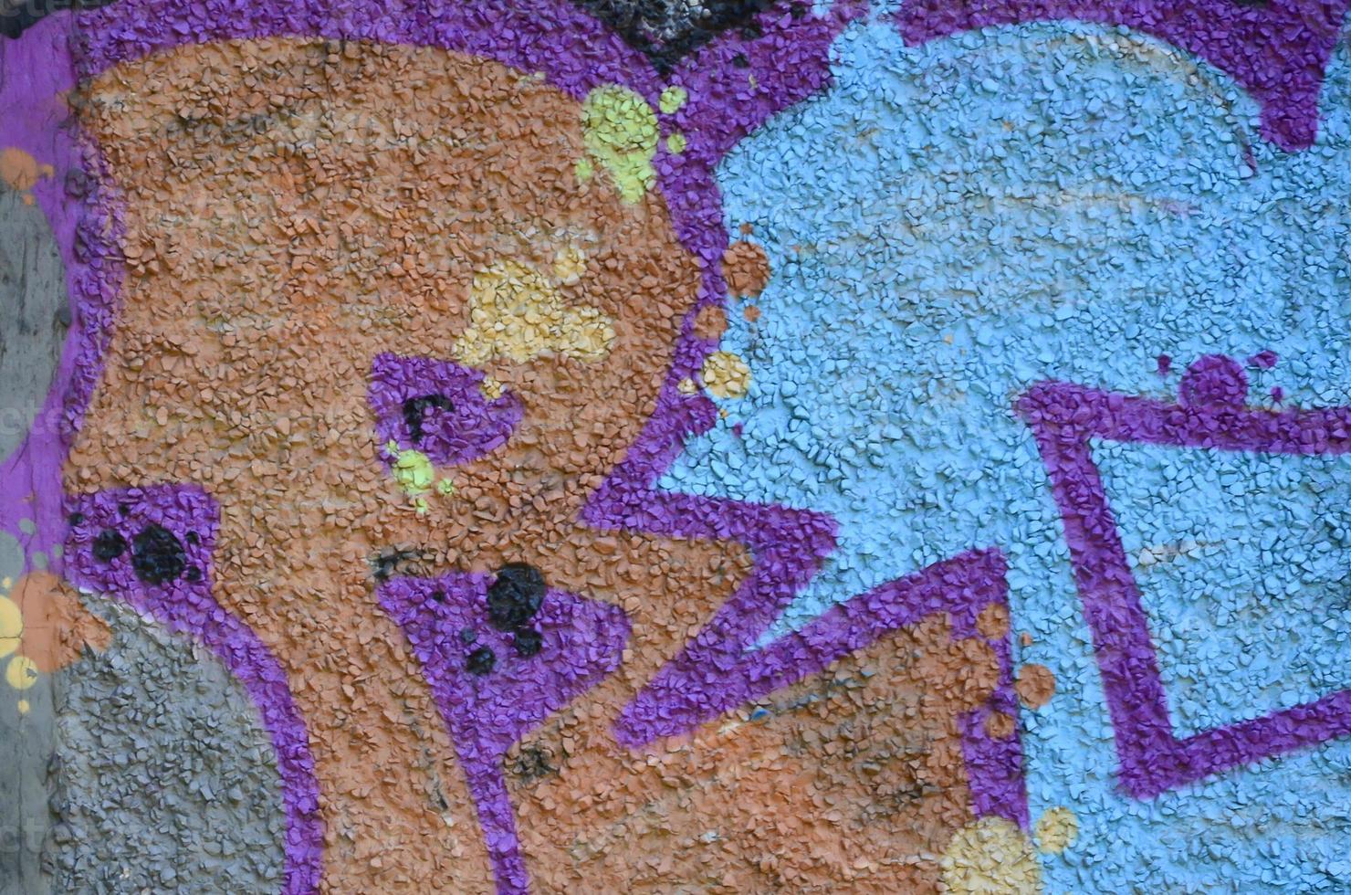 Fragment of graffiti drawings. The old wall decorated with paint stains in the style of street art culture. Colored background texture in warm tones photo